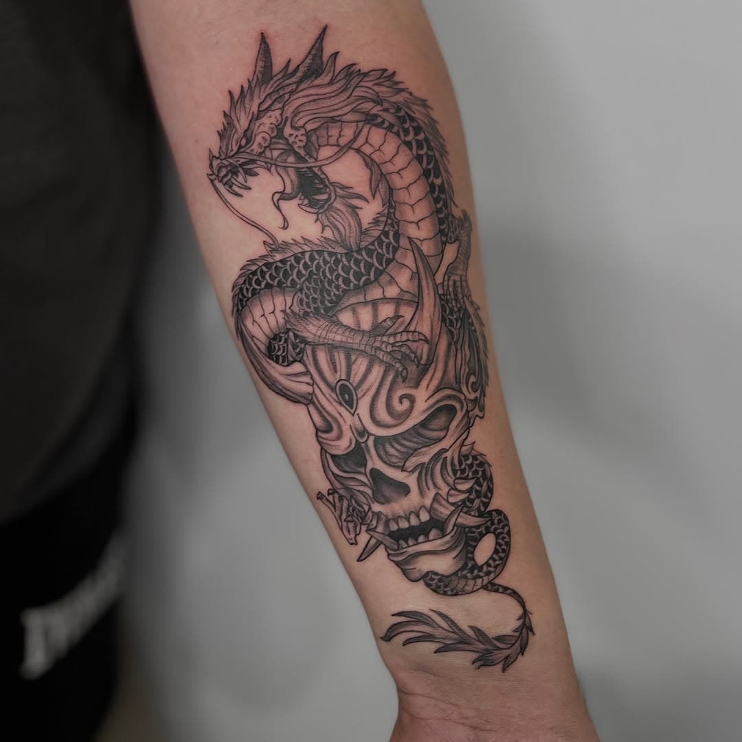 Black-and-grey Japanese dragon coiled over a horned hannya mask and skull on the forearm by AinsleyXTattoos