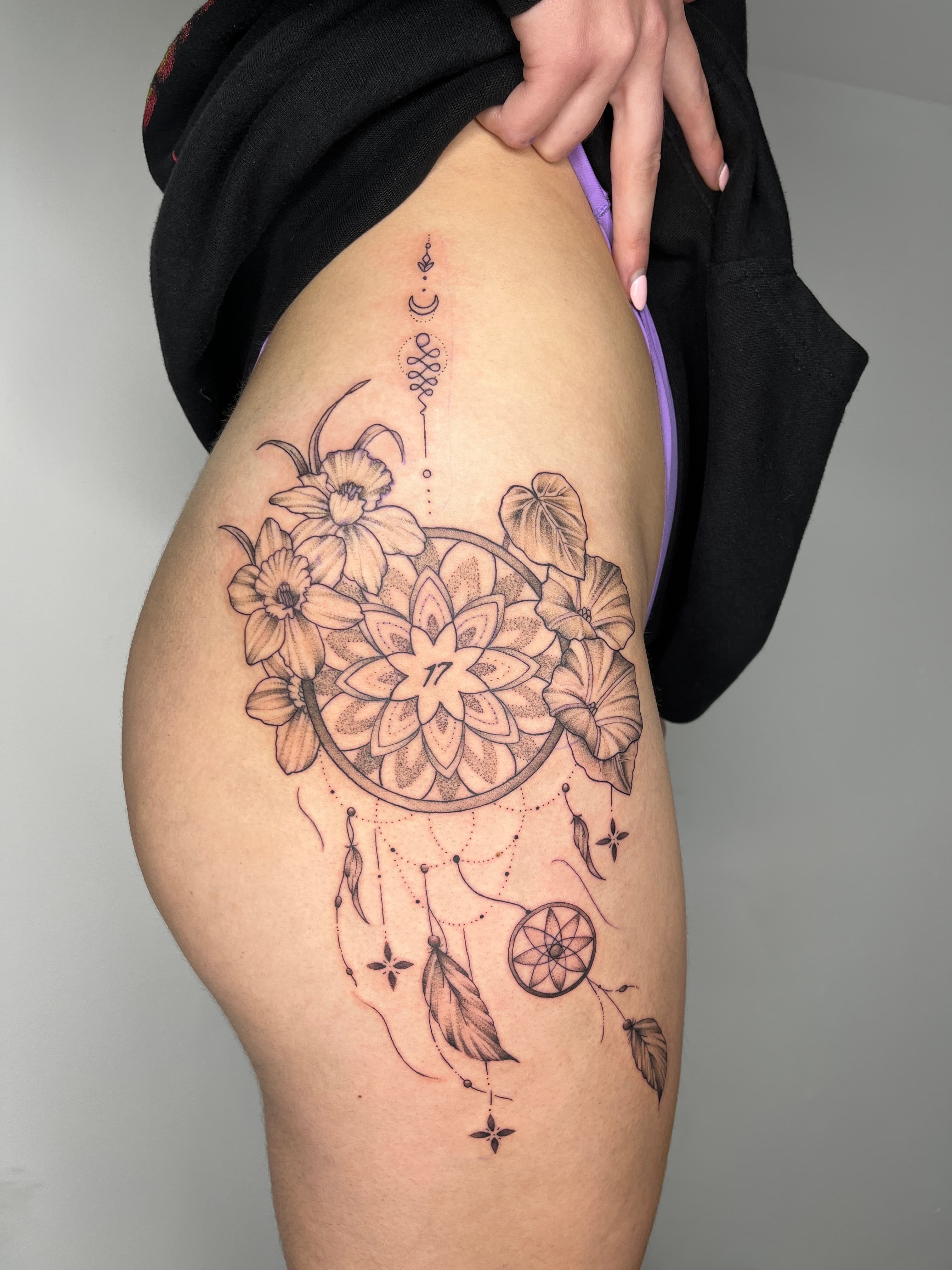 Fineline Black-and-grey dreamcatcher with beautiful floral on the thigh by AinsleyXTattoos